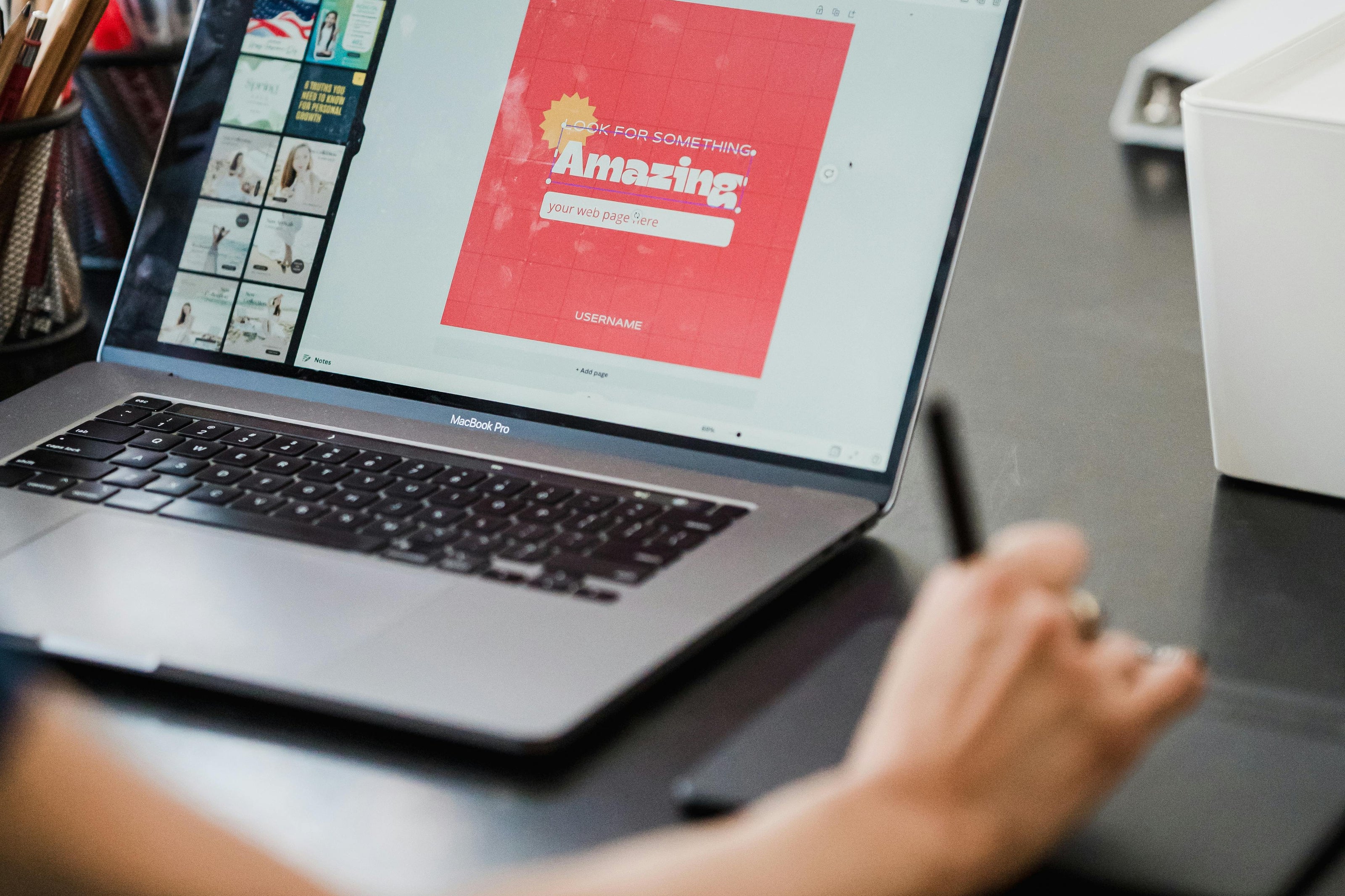 Person using a laptop with a graphic design on the screen at a desk.